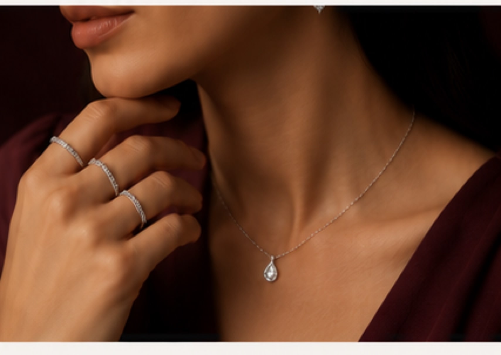 Model wearing stacked silver rings and a teardrop pendant necklace