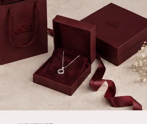 Signature burgundy KANZ packaging with a silver pendant necklace